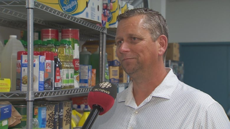 A man stands in front of shelf at a food bank.