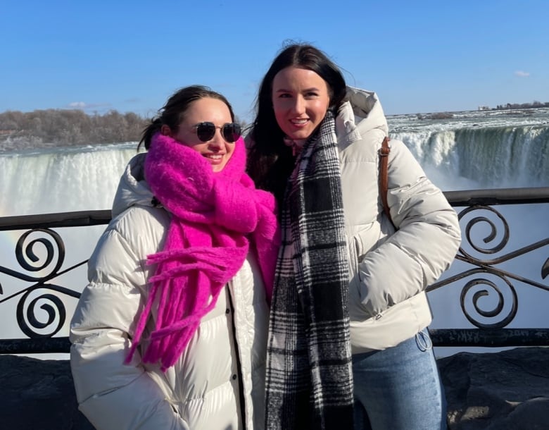 Two women, bundled up, stand in front of Niagara Falls.