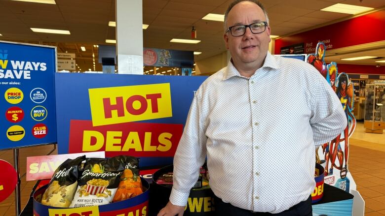 A man stands in front of signs offering hot deals.