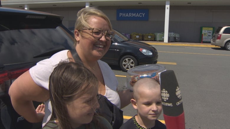 A woman is seen with her two children in a supermarket parking lot.