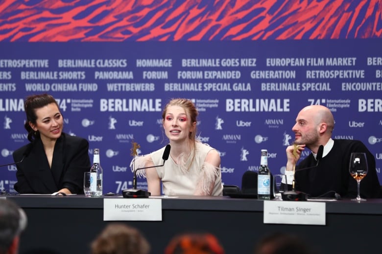 Three people speak at a podium.