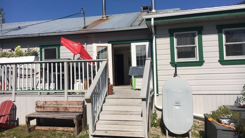 A house with a porch, a garden bed, oil tank.