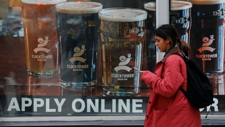 A woman walks by a window with a sign that says 