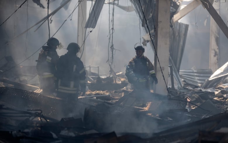 Emergency workers stand inside a destroyed building.