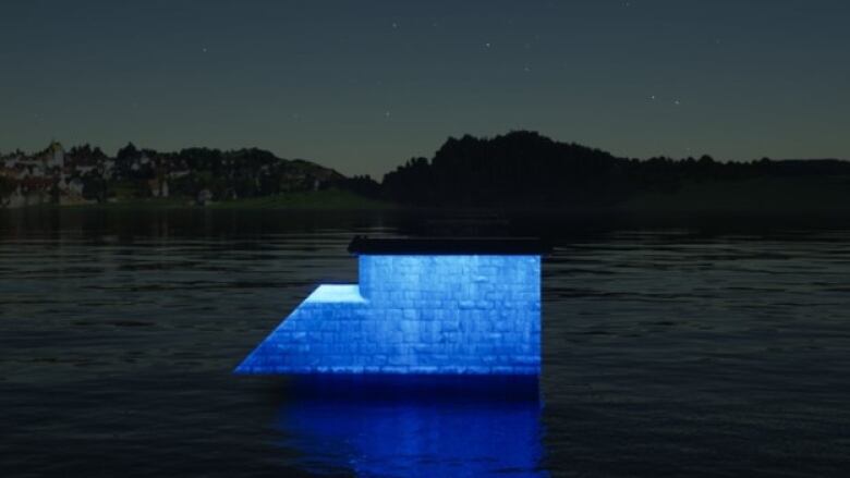 A bridge pier lit up in blue at night time in a river.