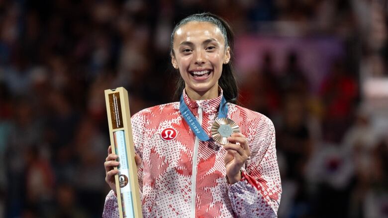 A woman poses with an Olympic medal.