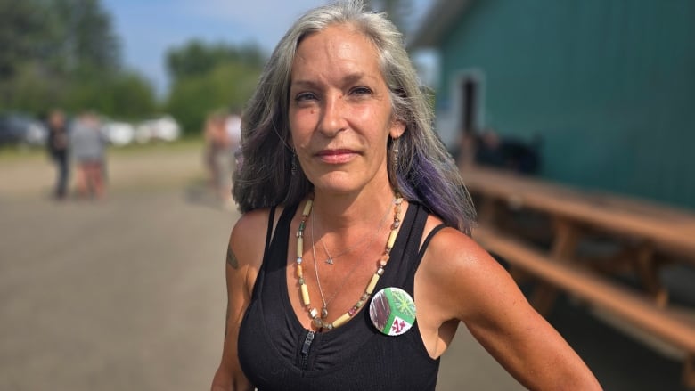 Woman with long, greying dark hair looks directly at the camera.