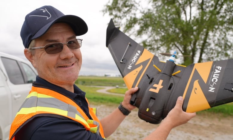 Man holding drone near runway.