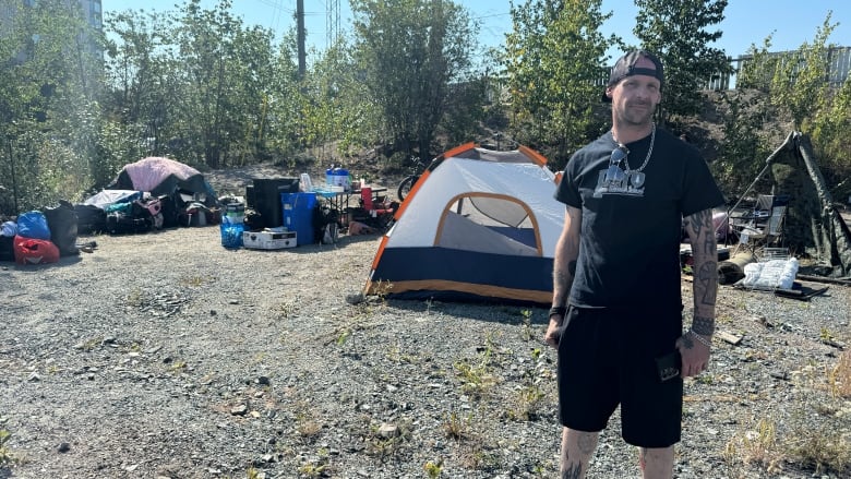 Man stands in front of tent encampment