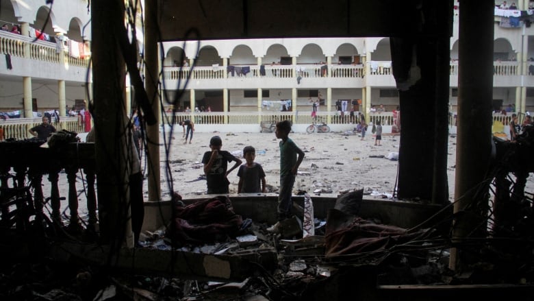 People survey damage to a building hit by a rocket.