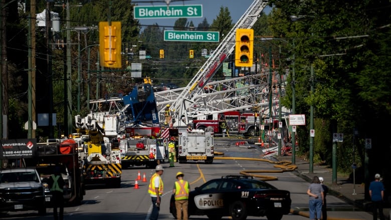 A crane lays across West 41st Avenue, surrounded by fire trucks and construction crews