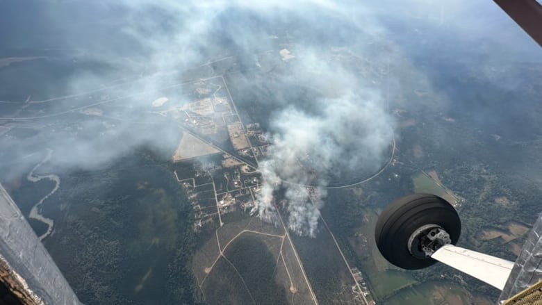 Smoke and haze arise from the ground, as pictured from a plane. The smoke seems to be just below the aircraft and near a few roads.