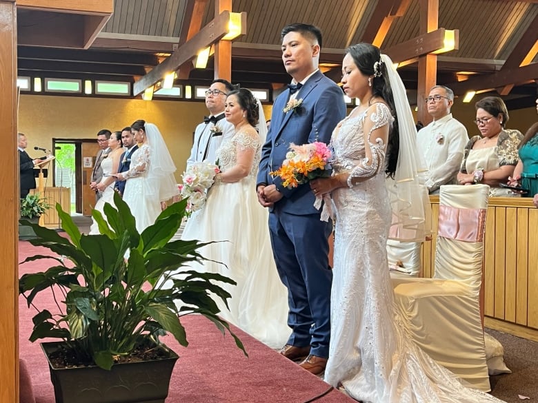 Four couples wearing bridal artier standing in front of a church alter. 