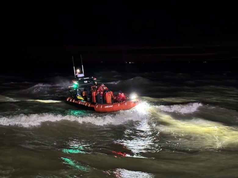 An orange boat in dark water with waves around it