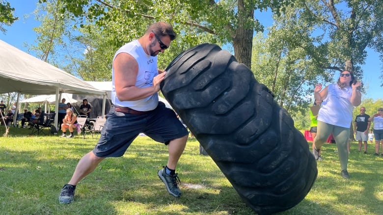 A man flips a 600lb large black tire.