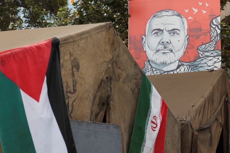 A banner featuring an illustration of a person is displayed next flags draped on a structure.