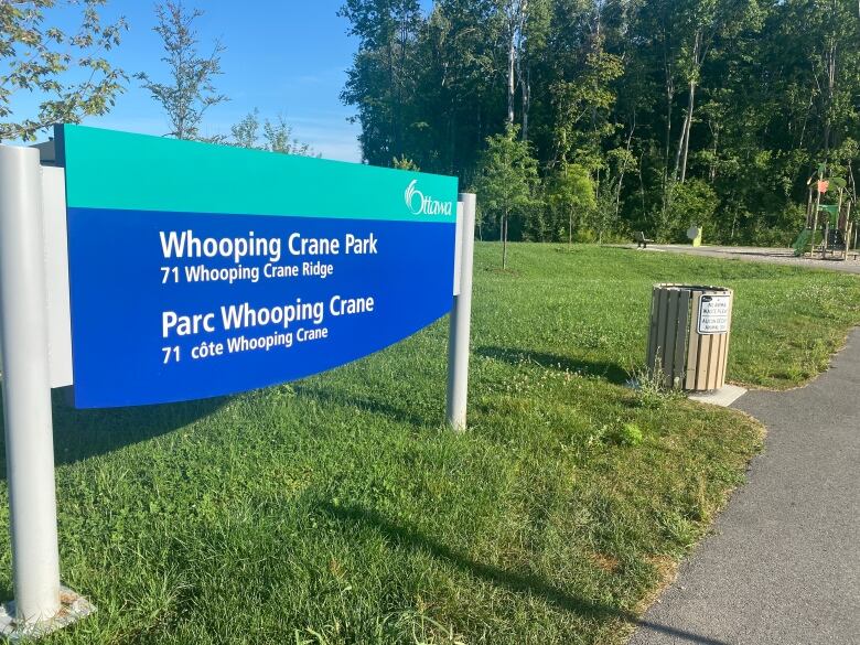 A sign with the park's name sits in front of a garbage bin. 