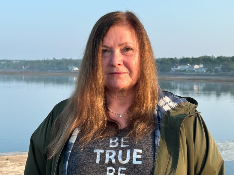 A white woman with brown hair. She is standing at a wharf.