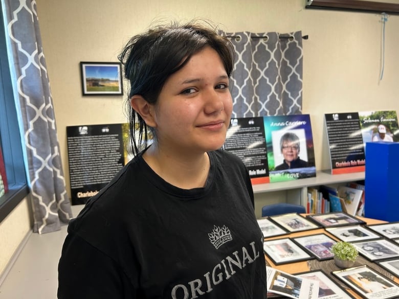 A girls in a black T-shirt poses in front of a photo display.