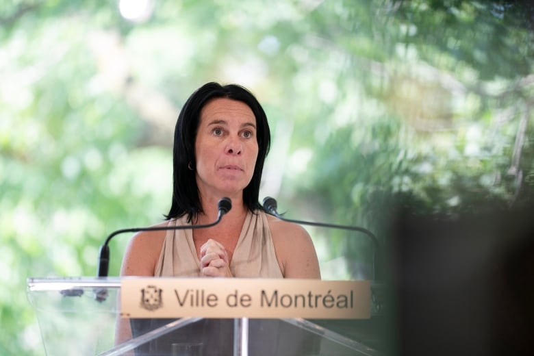 Valrie Plante wearing a beige halter top speaking at a podium that says 