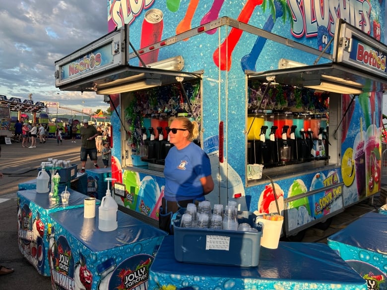 Woman with blond hair and blue shirt working at the carnival concession stand.