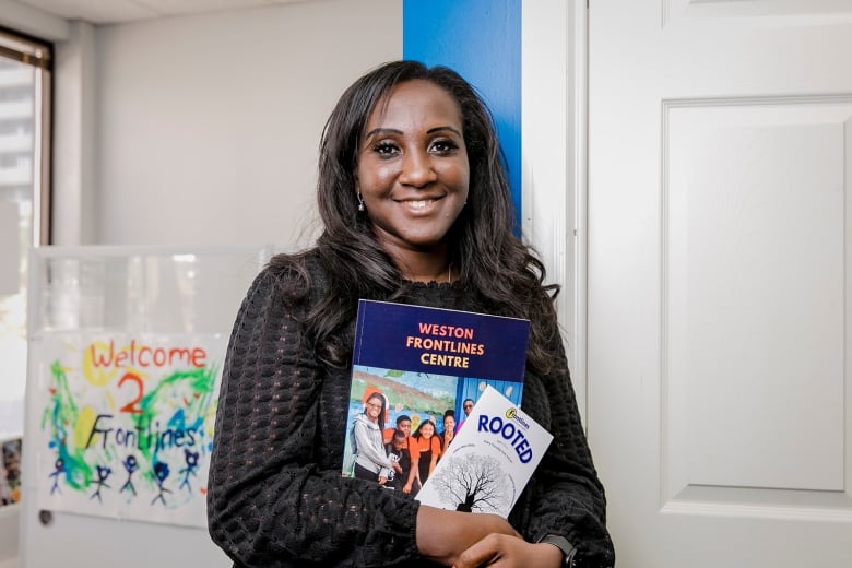 A woman holding a book and a pamphlet.