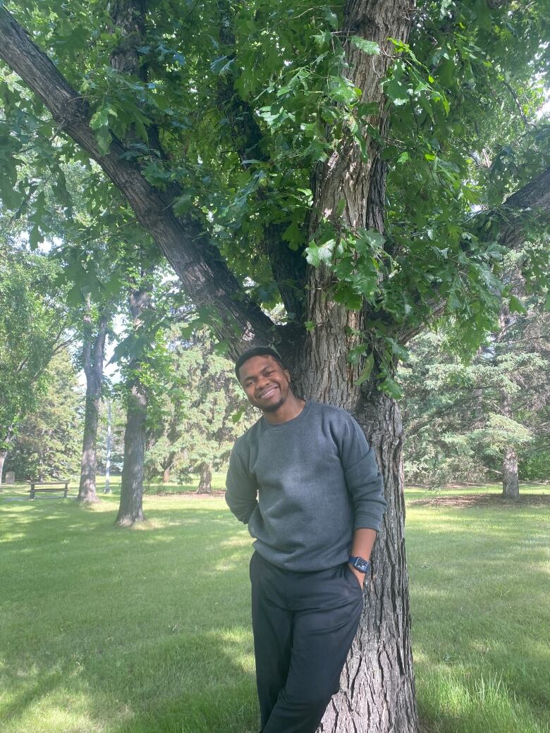 A man leans against a tree. 