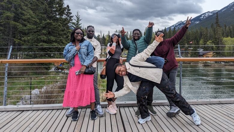 A group of people pose for a photo on a bridge with trees and a river in the background. 