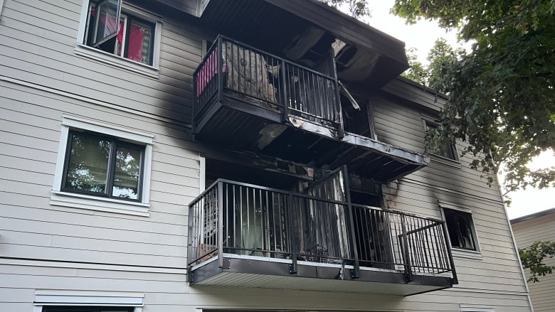 A low-rise apartment building with vinyl siding. Blackened exterior.