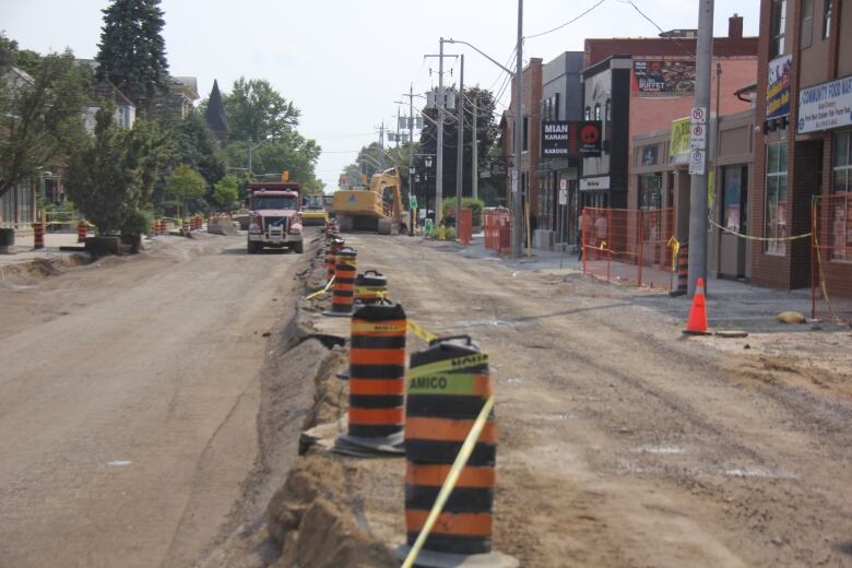 Construction cones on a dirt road and heavy machinery working in the background.