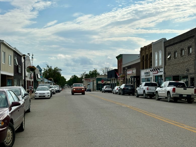 Main Street in Moosomin with businesses, parked cars and jeep driving down road