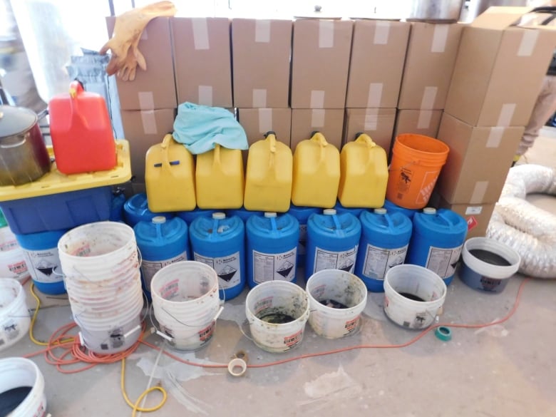 Large bottles and paint canisters are pictured in a disorganized fashion.