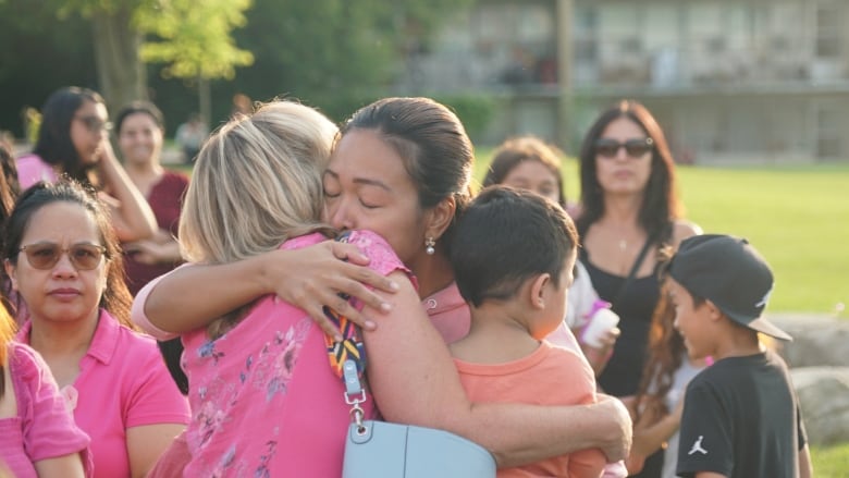 Karen Fermill, right, holds her son while hugging a community member who arrived at Wednesday's vigil to support her family.