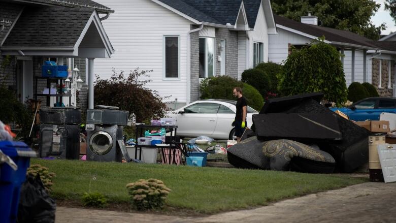 Discarded items sit on a lawn as someone wearing gloves walks by. 