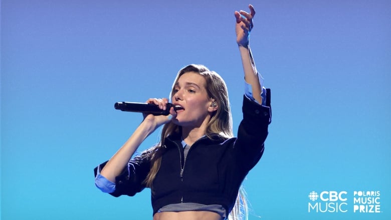 Charlotte sings into a mic at the 2024 Junos while wearing a blazer top and matching skirt.