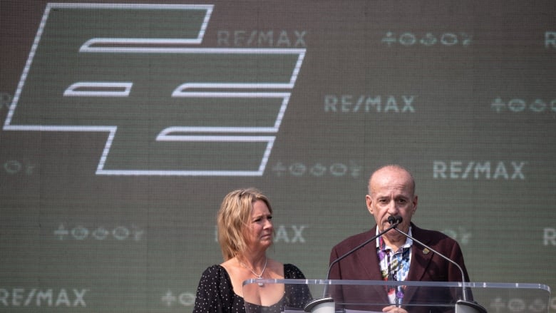 A woman and a man stand on a stage.