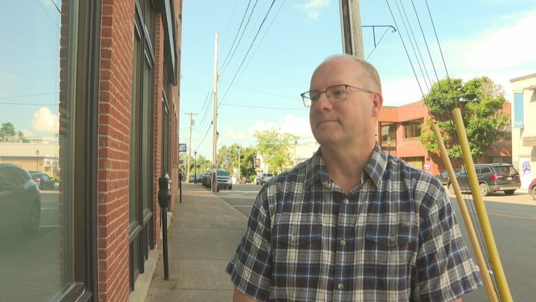 Man in plaid shirt and glasses looks off camera. 