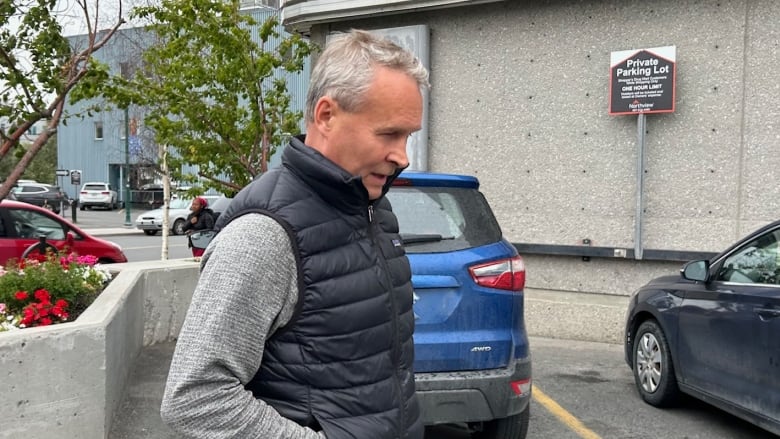 Man in a jacket walking in a parking lot.