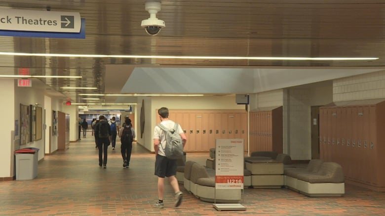 Students are seen walking down a university hallway.