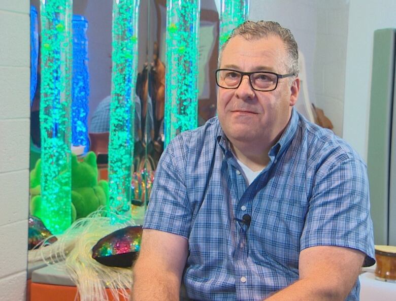 A man sits in front of a blue light