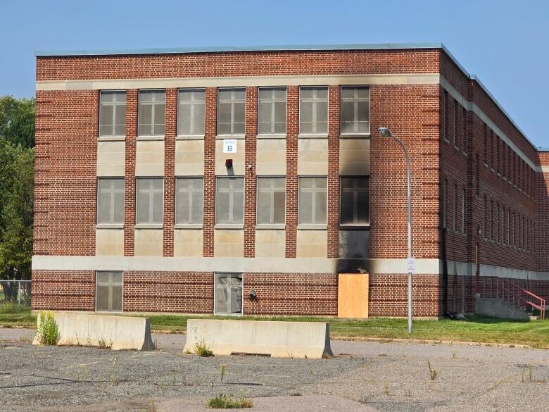 The exterior of a brick building with a boarded-up lower window and smoke damage.