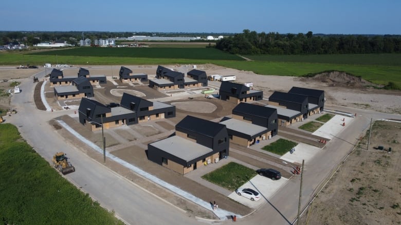 An aerial shot shows 28 housing units in a subdivision with dirt and some paved pathways.