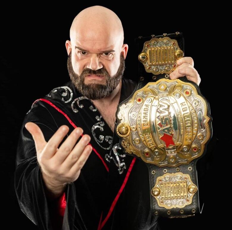 Vance Nevada looks menacingly into the camera while holding up a championship belt.