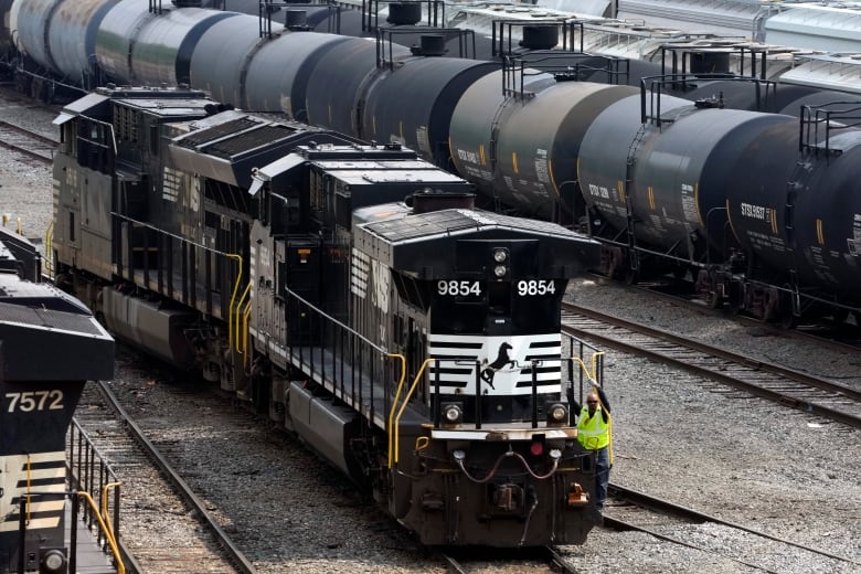 Trains sit on a track in a railyard.