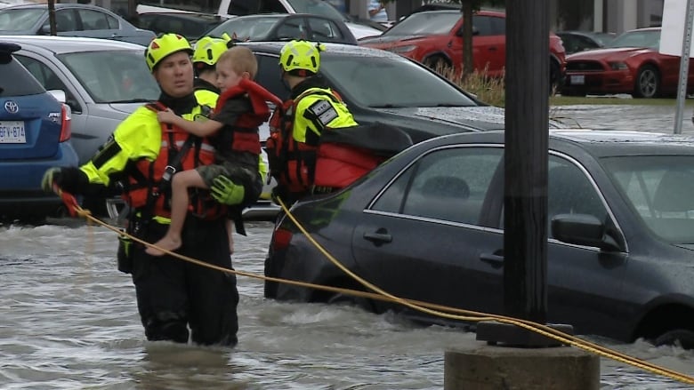 Photograph of a fireman holding a child, rescuing them in floodwater