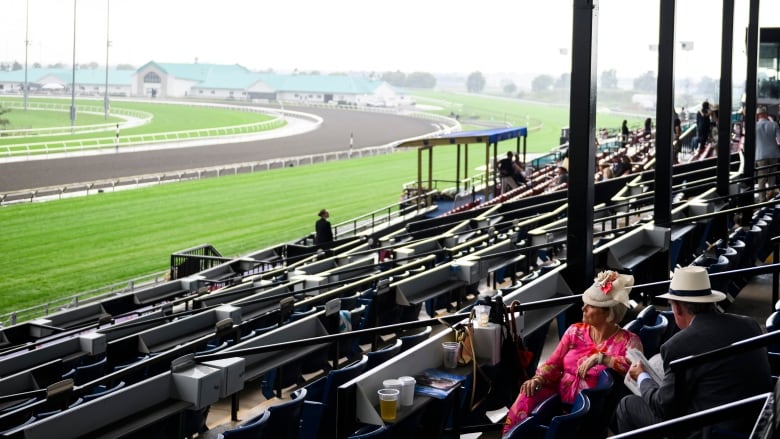 People sit in the grandstands of Woodbine Racetrack after a heavy downpour of rain resulted in the cancellation of part of the King's Plate, in Toronto on Saturday, August 17, 2024.