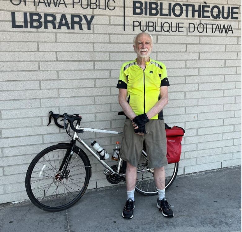 Man stands with bike outside library 