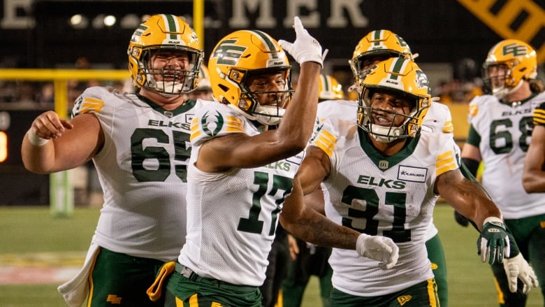 A group of football players celebrate in the end zone on the field after scoring a touchdown.