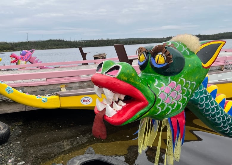 Three dragon boats are docked on two wharves.