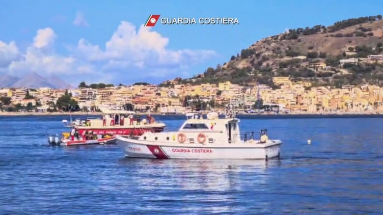 Two boats are shown on a body water with a hillside community shown in the background.